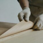 artisan ajustant une fine feuille de placage bois sur panneau