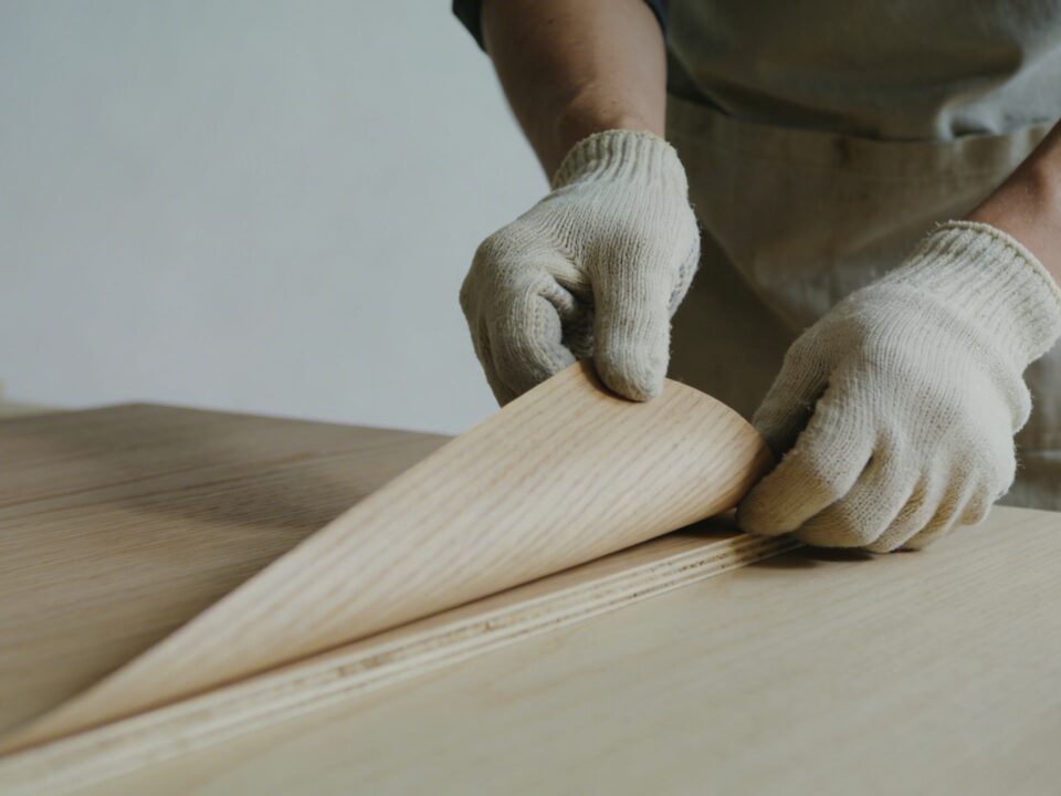 artisan ajustant une fine feuille de placage bois sur panneau