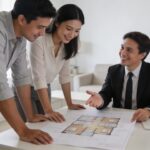 couple examine plan maison dans salon lumineux avec proprietaire souriant