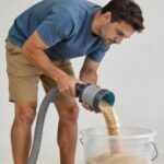 Homme vidant du sable de filtre piscine dans grand seau plastique