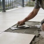 Macon agenouille sur terrasse exterieure nivelant chape beton avant carrelage